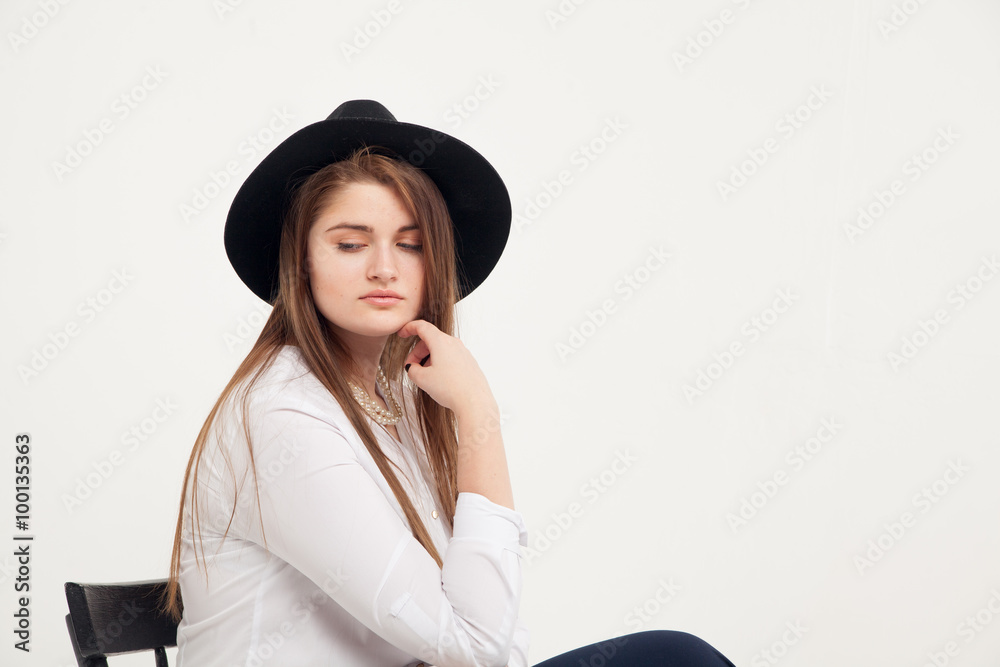 Awesome Caucasian attractive shy sexy female model with brunette hair posing on table in studio, wearing formal suit and hat, isolated on white background Awesome Caucasian attractive shy sexy female model with brunette hair posing on table in studio, wearing formal suit and hat, isolated on white background