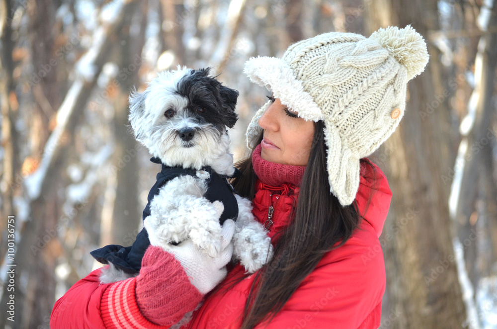 Young beautiful woman smiling and hugging her  dressed white poodle dog.Winter time