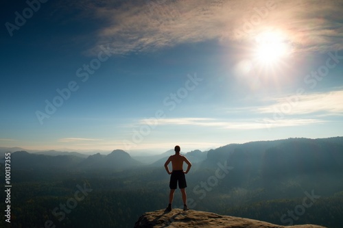 Climber in black pants. Gesture of triumph. Body naked man on the peak of sandstone rock in national park Saxony Switzerland