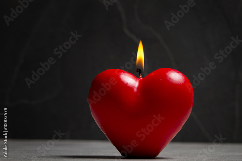 Świeczka w kształcie serca na kamiennym tle 