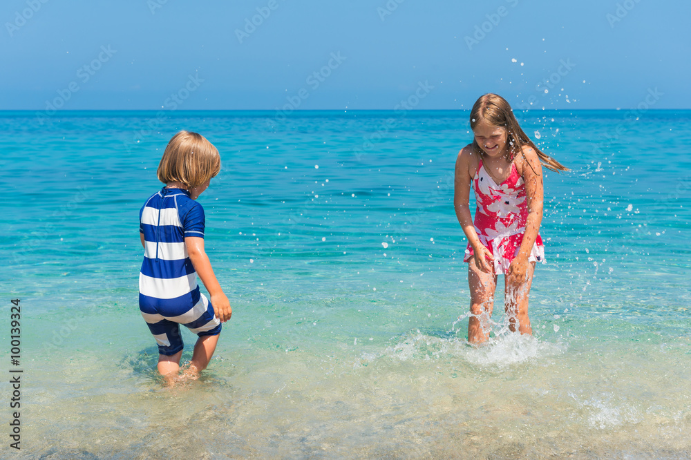 Two kids having fun on summer vacation, playing in the sea, image taken in Tropea, Calabria, Italy