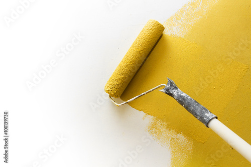 Fototapeta Naklejka Na Ścianę i Meble -  Paint roller applying paint on white wall, home improvements