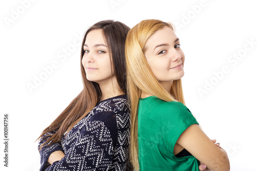 Closeup portrait of two teenage girls standing back to back with