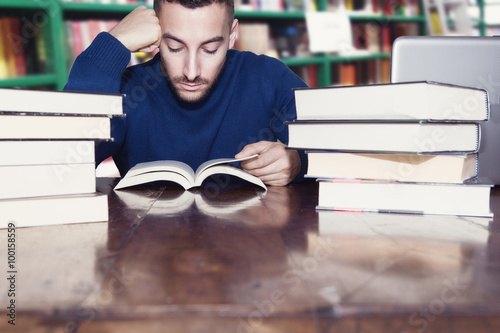 uomo legge libri in biblioteca photo