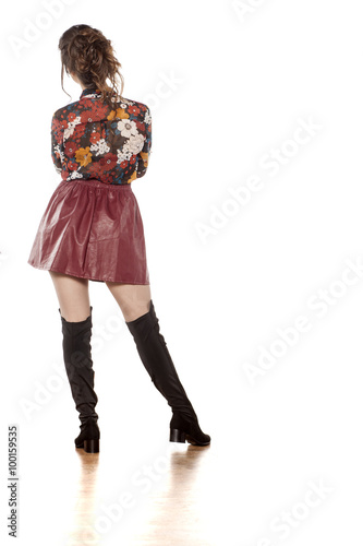 back view of attractive brunette in a leather skirt and boots