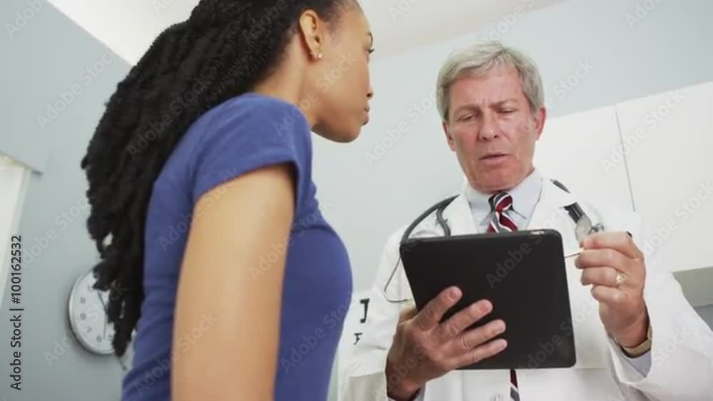 Senior doctor looking over African woman's medical history Senior doctor looking over African woman's medical history