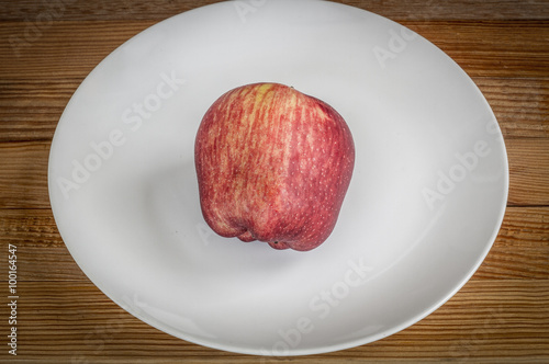 Red apple in white dish on wooden background