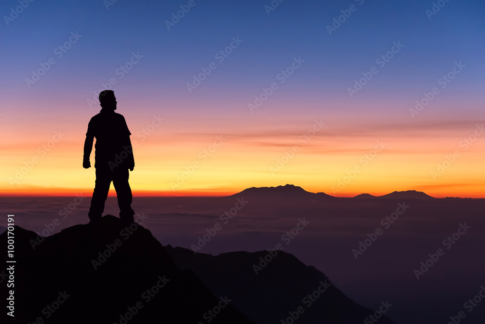 silhouette of man standing on the top of mountain to enjoy colou