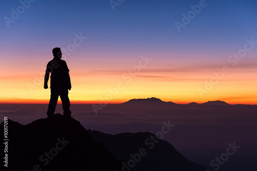 silhouette of man standing on the top of mountain to enjoy colou