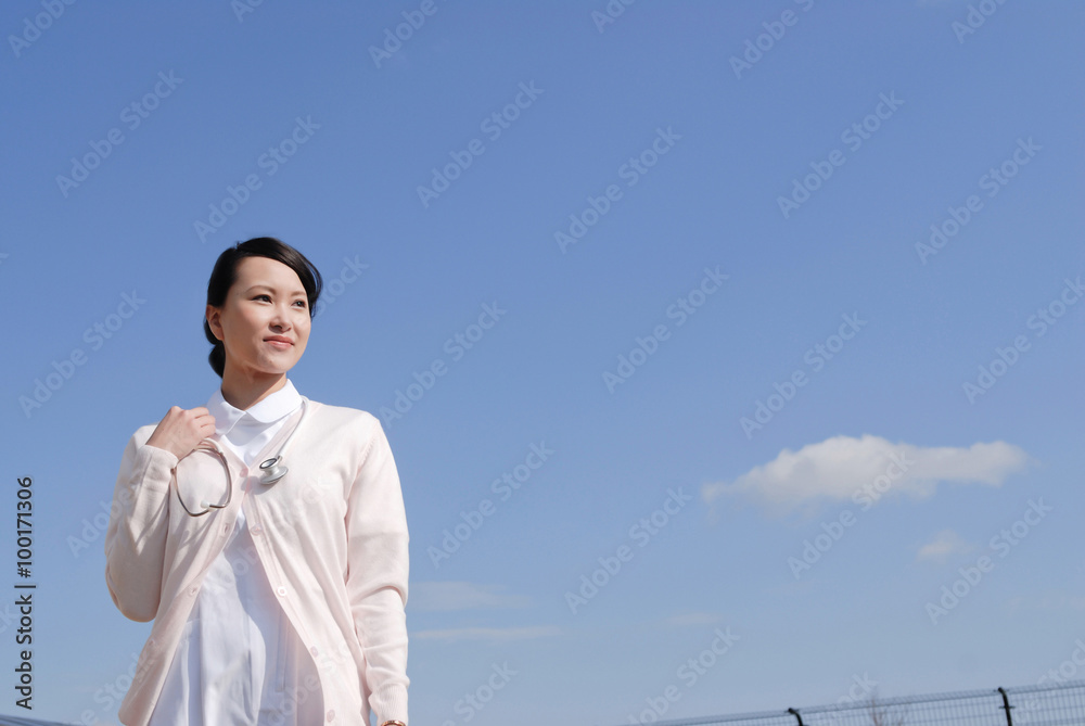 青空を背景に立つ女性看護師 青空を背景に立つ女性看護師