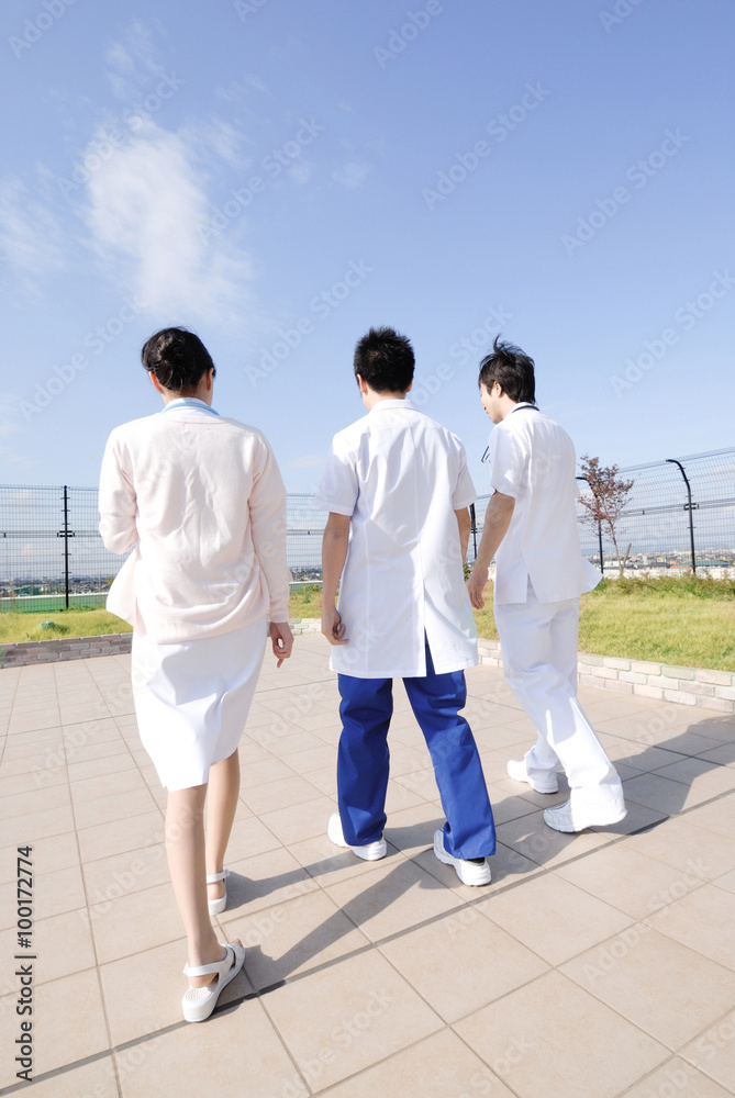 病院の屋上を歩く男性医師2名 女性看護師の後姿 Stock Photo Adobe Stock