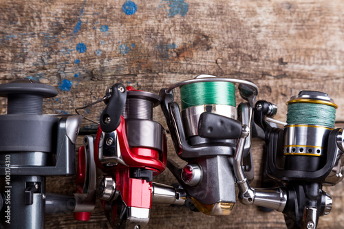 different fishing reels with line on wooden background