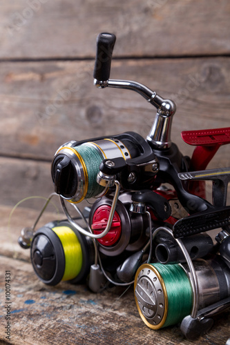 different fishing reels with line on wooden background