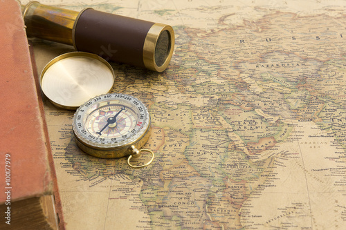 Old book and old spyglass and old compass on vintage map world discovery concept