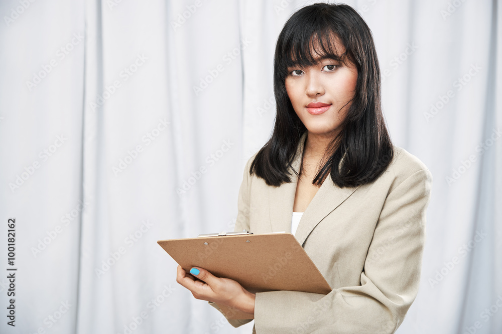 close up of businesswoman wearing beige suit standing and taking note on folder close up of businesswoman wearing beige suit standing and taking note on folder