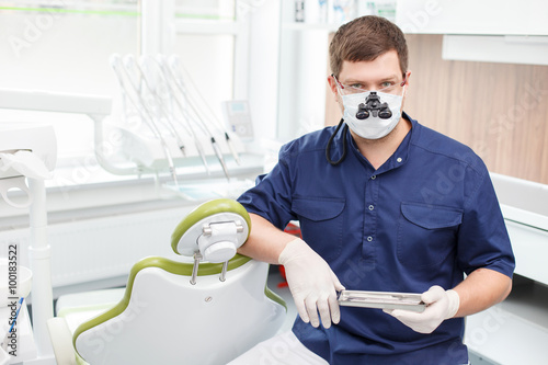 Handsome dental doctor is working with modern equipment photo