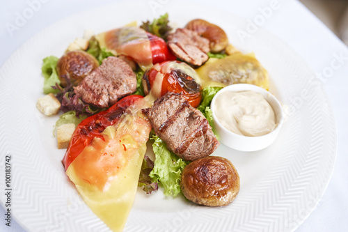 Warm salad with veal on white plate studio shot