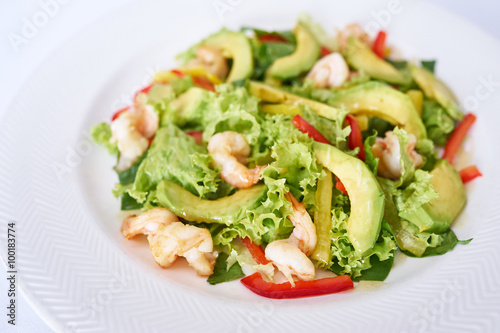 Avocado salad with shrimp on white plate studio shot