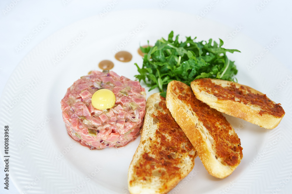 Tartare of veal on white plate studio shot