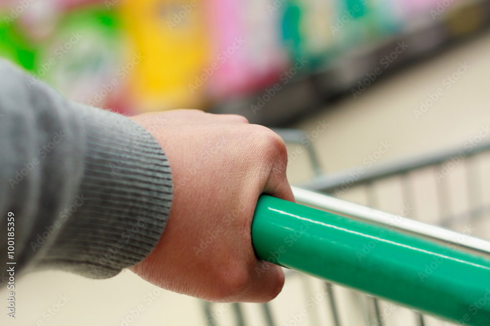 Closeup hand and shopping cart at supermarket