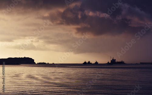 Cargo ships in horizon on sunset in Marsaxlokk, Malta