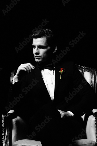 Portrait of man who sitting on chair, godfather-like character.