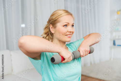 woman exercising with dumbbells on mat at home