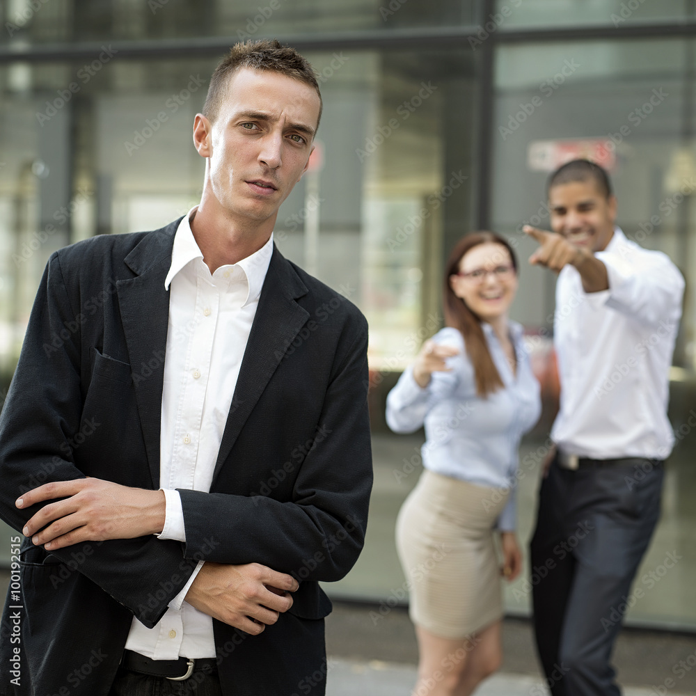 Gossip colleagues in front of their office, businessman portrait and gossiping out of focus in background. Gossip colleagues in front of their office, businessman portrait and gossiping out of focus in background.