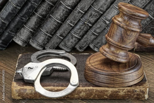 Handcuffs, Judge Gavel And Old Law Books On Wooden Table photo