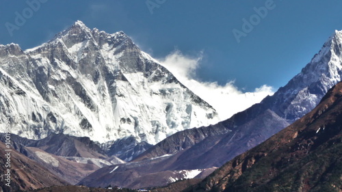 Time-lapse of the tip of Everest and surrounding peaks and trekkers on a foreground trail. . Cropped. photo