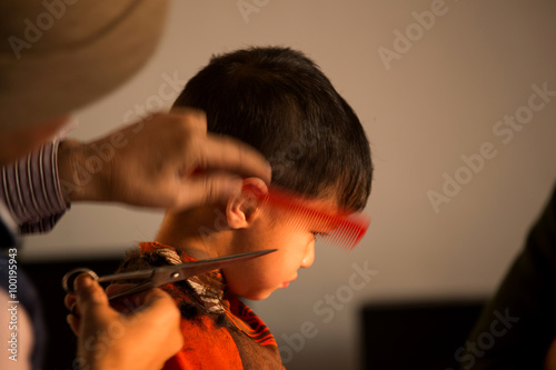two year old kid having a haircut  with wet eyes after crying early morning with golden light falling on his face