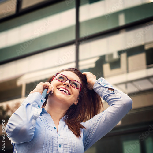 Successful business woman is talking on mobile phone and smiling. Shallow depth of field.