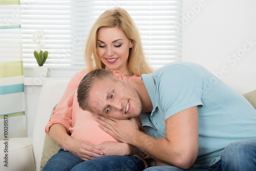 Man Listening To Pregnant Woman's Belly At Home