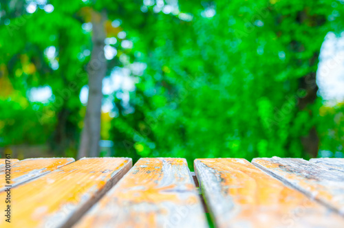 Yellow wooden planks with blurred green foliage