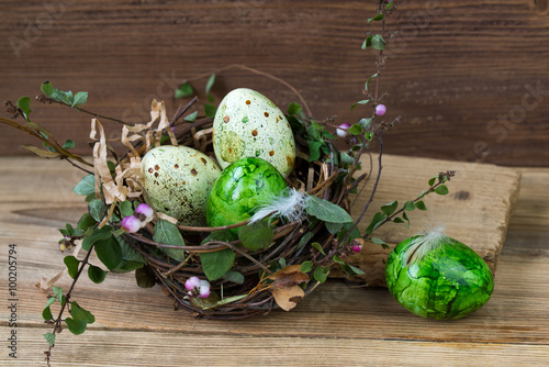 Nest with colored Easter eggs on wooden background