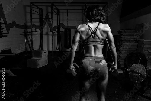Black and white image of Woman working out in a gym with weights