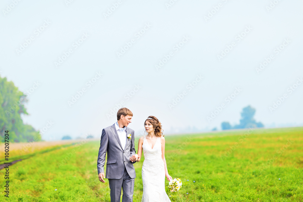 happy beautiful bride and groom walking on field happy beautiful bride and groom walking on field