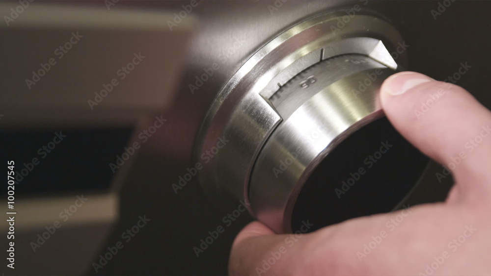 Close-up shot of a hand turning a safe dial.