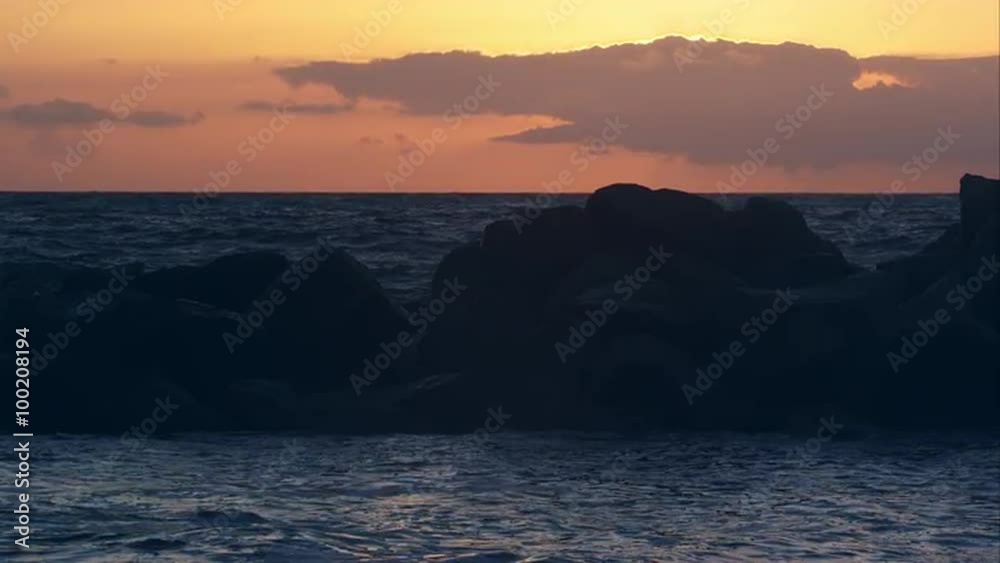 Slow motion view of waves crashing on rocks at sunset on Venice Beach.