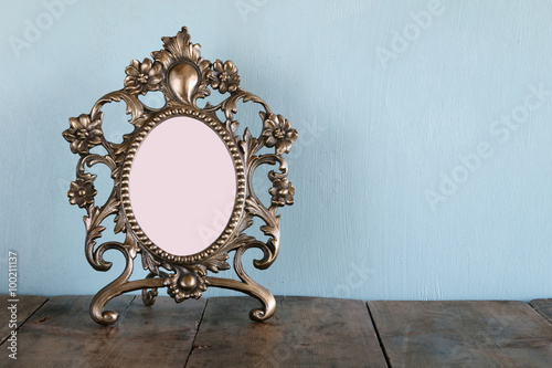 Antique blank victorian style frame on wooden table. retro filtered image. template, ready to put photography 