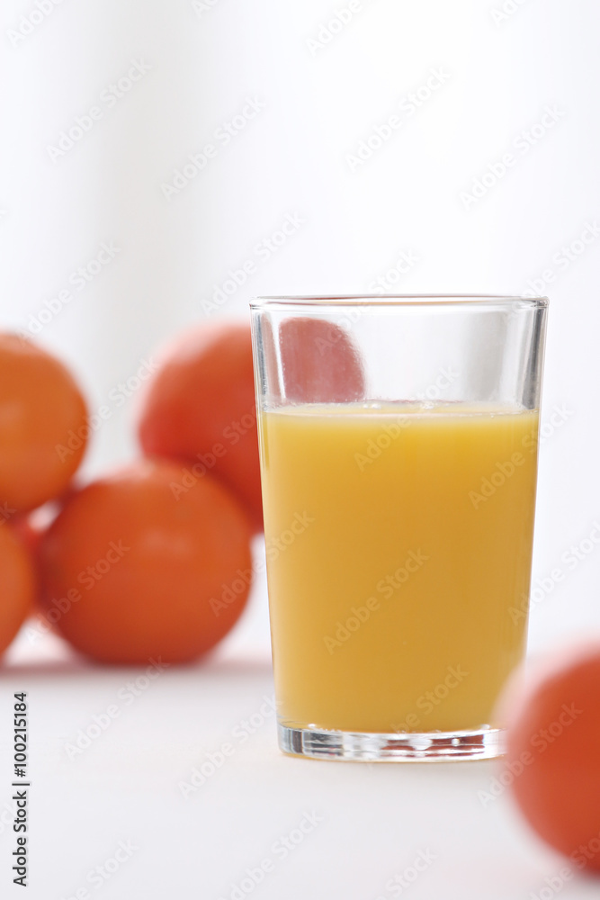close-up on a full of vitamins glass of orange juice with oranges in the background close-up on a full of vitamins glass of orange juice with oranges in the background