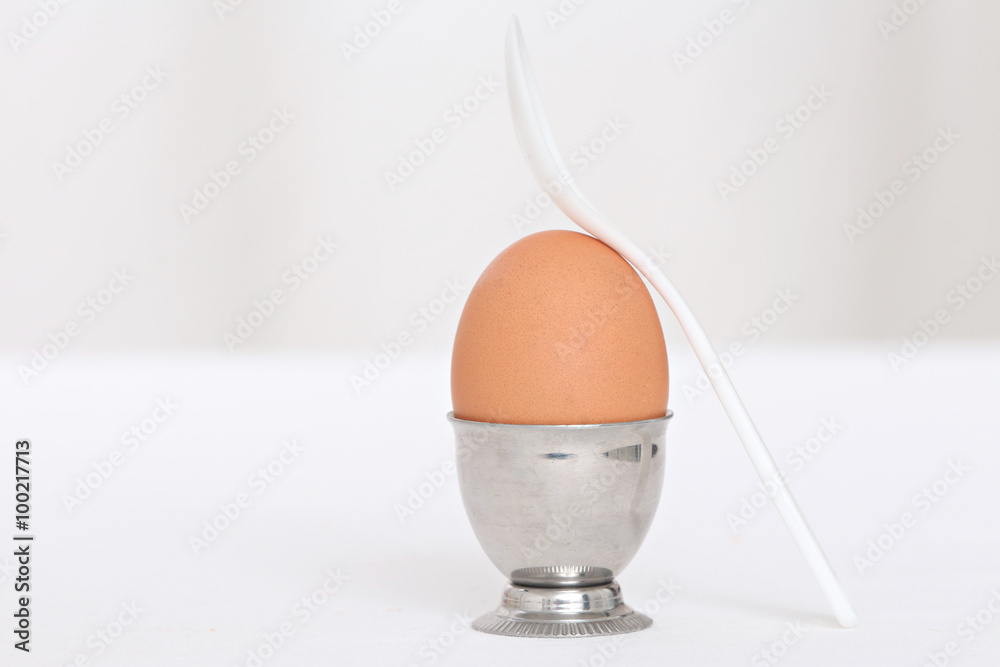 close up of one whole egg in an eggcup with a spoon next close up of one whole egg in an eggcup with a spoon next