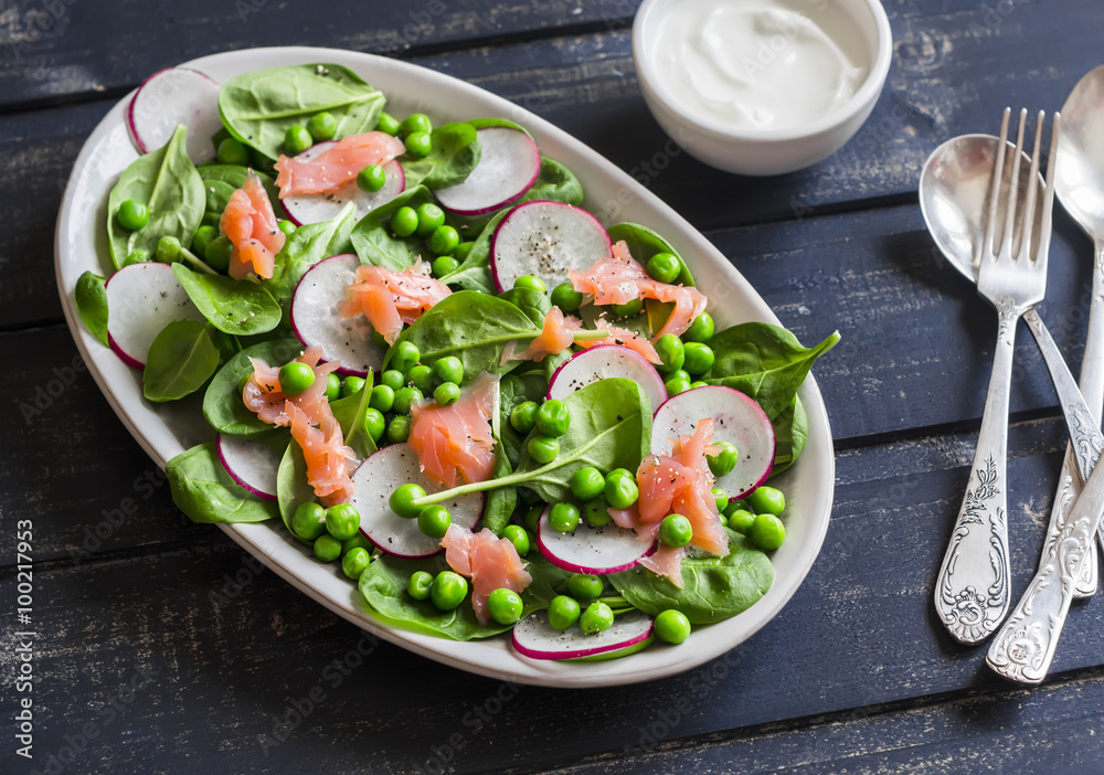 Smoked salmon, spinach, green pea and radish salad.  Delicious lunch. On a dark background