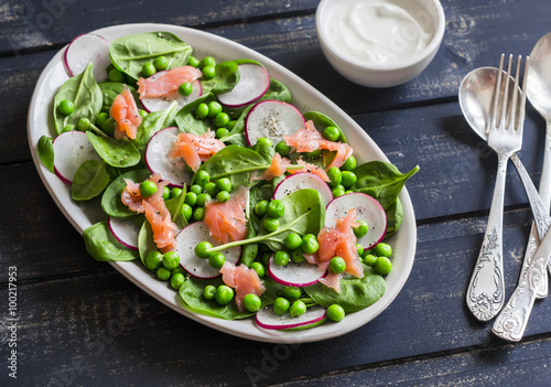 Smoked salmon, spinach, green pea and radish salad. Delicious lunch. On a dark background