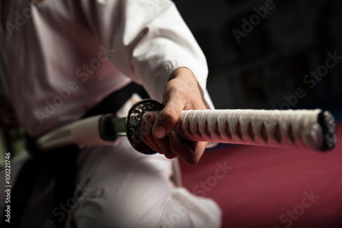 Close uo of young martial arts fighter with katana siting in seiza position