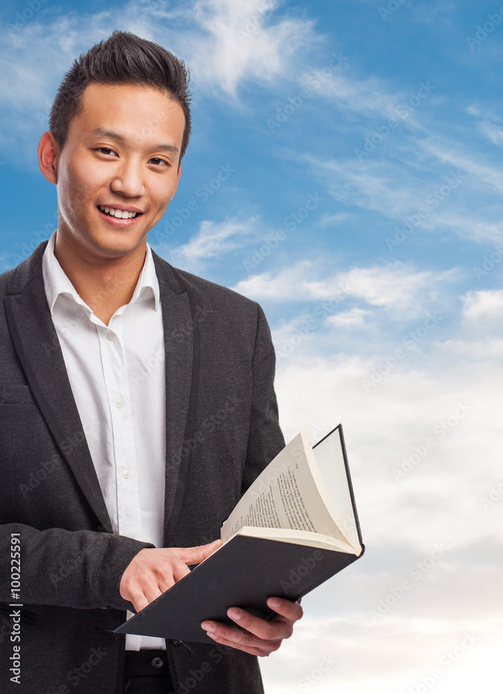 portrait of handsome young asian man holding a book