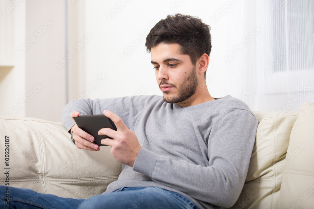 Handsome casual young man using a tablet at home