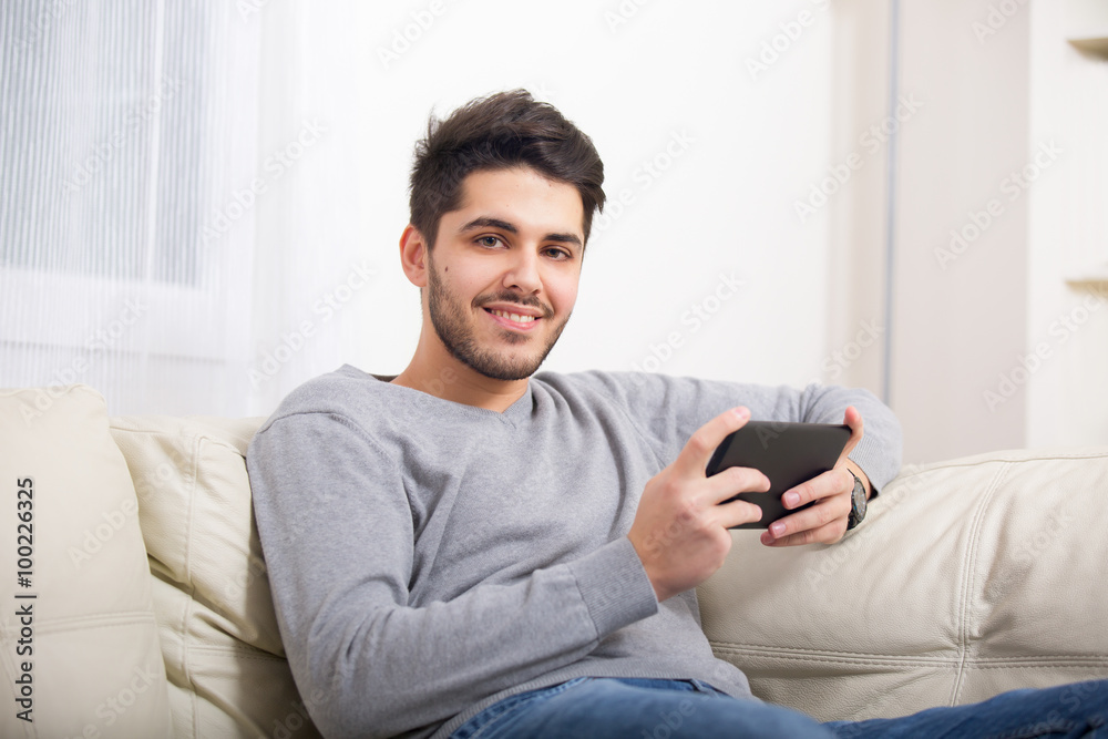 Handsome casual young man using a tablet at home Handsome casual young man using a tablet at home