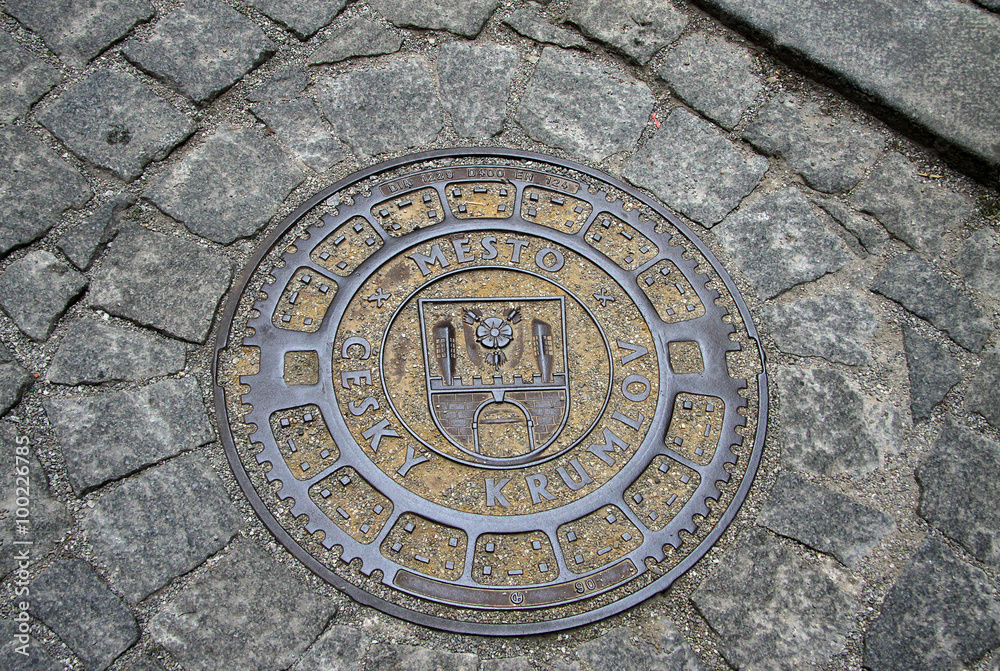 CESKY KRUMLOV, CZECH REPUBLIC - MAY 01, 2013: Round steel sewer manhole on old cobblestone road in Cesky Krumlov, Czech Republic