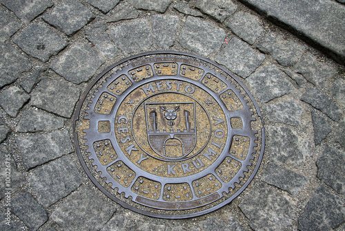 CESKY KRUMLOV, CZECH REPUBLIC - MAY 01, 2013: Round steel sewer manhole on old cobblestone road in Cesky Krumlov, Czech Republic